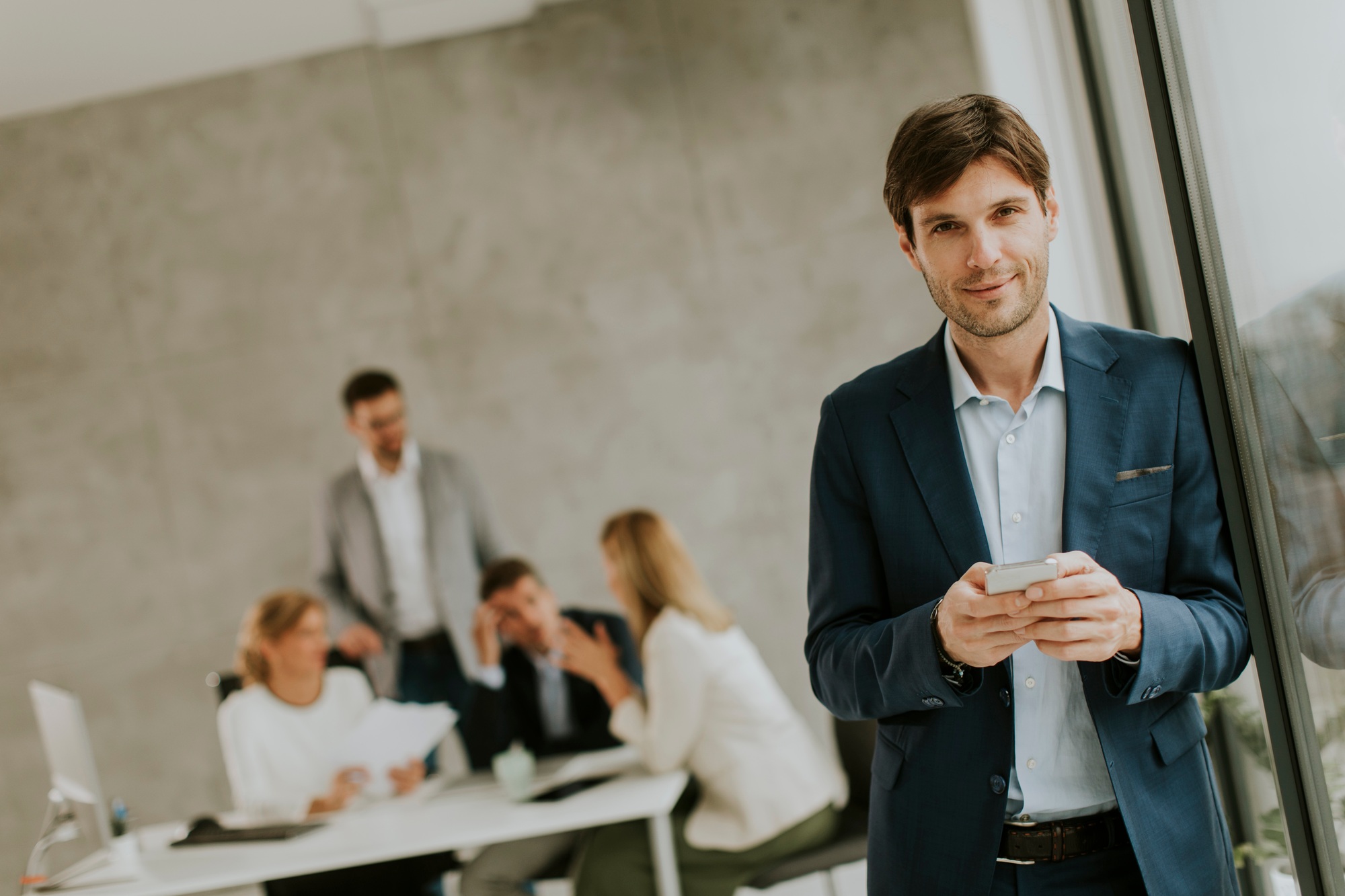 Handsome young business man standing confident in the office and suing mobile phone